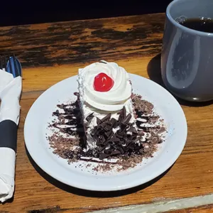 Celebrate Oktoberfest with a Pig & Duke Food Special: $6.95 • Fill your sweet tooth with a slice of Black Forest Cake! (GST Not Included | House Rules Apply) [Picture: Pig & Duke Plated Pig & Duke Black Forest Cake and a coffee]