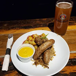 Celebrate Oktoberfest with a Pig & Duke Food Special: $22.95 • Fill up with the star of the show! Beer Braised Sausage & Kraut with warm German potato salad along with a mustard dip! (GST Not Included | House Rules Apply) [Picture: Pig & Duke Plated Pig & Duke Beer Braised Sausage & Kraut and a Paulaner Pint]